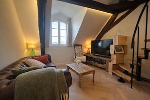 Een gezellige loft-achtige woonkamer met een leren bank, een houten salontafel, een flatscreen-televisie en een wijnrek.