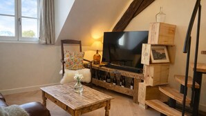 Ein Loft-Wohnzimmer mit niedrigem TV-Schrank, einer Couch, einem Couchtisch und einer Treppe.