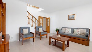A living room with a sofa, two armchairs, a coffee table, and a wooden staircase. - Apartment 'Galego C' with Shared Pool, Shared Garden and Wi-Fi (Olhos de Água)
