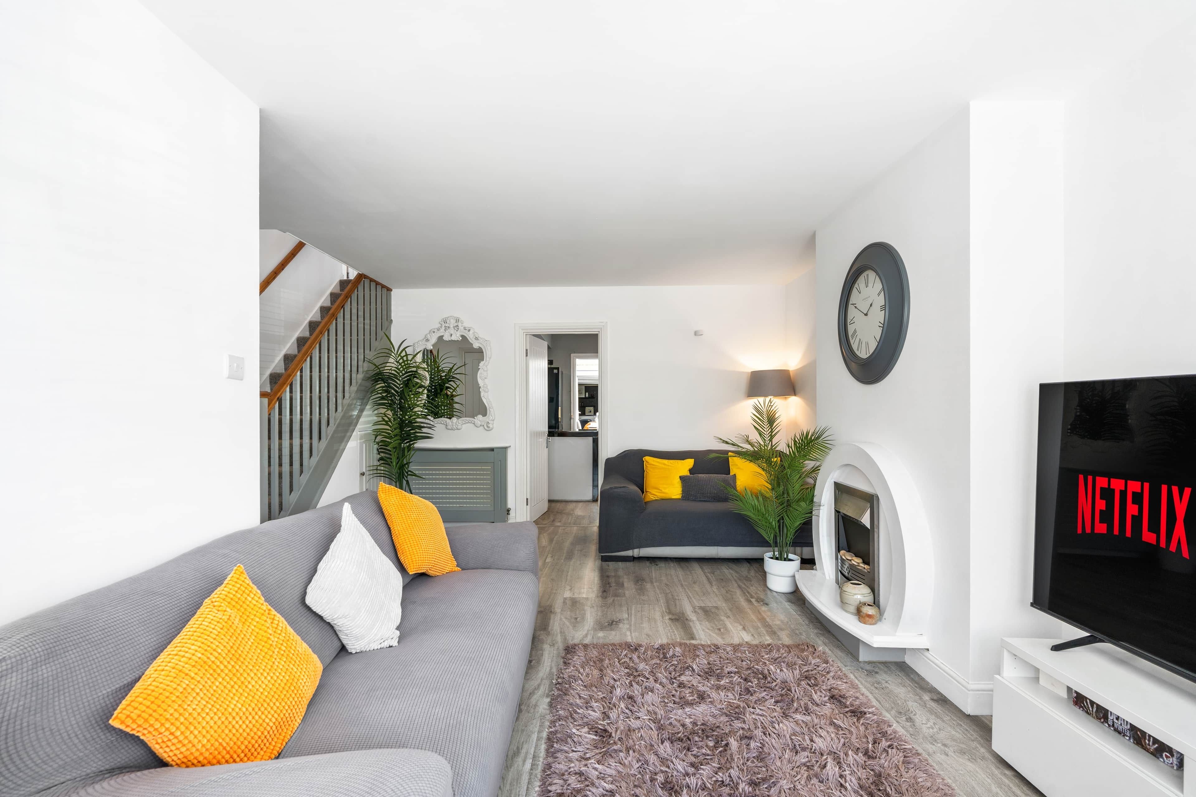 Een moderne woonkamer met een grijze bank, een televisie en een open haard.