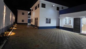A building with a paved courtyard, multiple windows, and a sign on the wall.