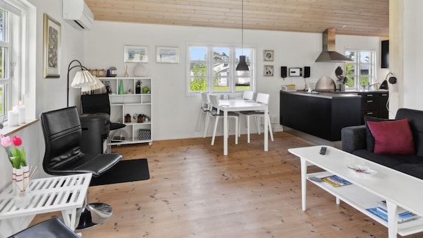 Un salon moderne comprenant un coin repas, une cuisine et une grande fenêtre laissant entrer la lumière naturelle.
