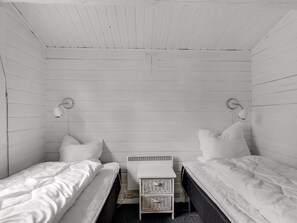 A small, white-paneled room with two single beds, a small table, and two wall-mounted lamps. - "Jalina" - 30km from the sea by Interhome (Toftlund)