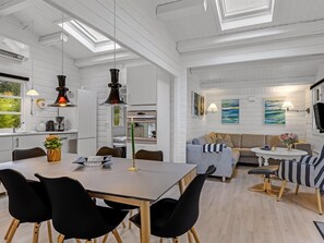 A modern kitchen with white cabinetry, a dining area with a table and chairs, and a living space with a sofa and a TV. - "Jalina" - 30km from the sea by Interhome (Toftlund)