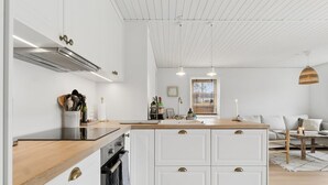 Une cuisine moderne avec des meubles blancs, un plan de travail en bois et un four encastré.