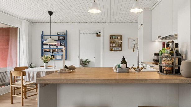 Une cuisine moderne dotée d’un îlot central, de tabourets en bois, d’une bibliothèque et de divers ustensiles de cuisine.