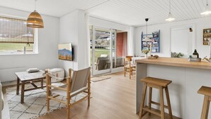 Une cuisine moderne avec un îlot central en bois, des tabourets de bar et un coin repas comprenant une table et des chaises.