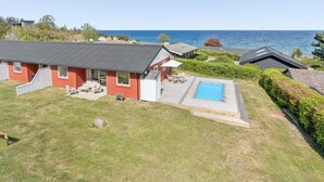 Une propriété résidentielle dotée d’une piscine, d’un patio couvert et offrant une vue sur la mer.