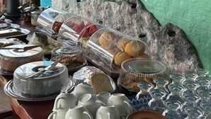 A buffet setup with food items, serving dishes, and utensils. - Pousada Villa Japa (Maragogi)
