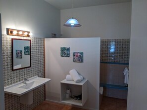 A bathroom with a sink, mirror, towel rack, and a shower area.