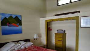 A bedroom with a bed, a painting, a dresser, and a door leading to another room. - La Sagesse Bay View (St. David)