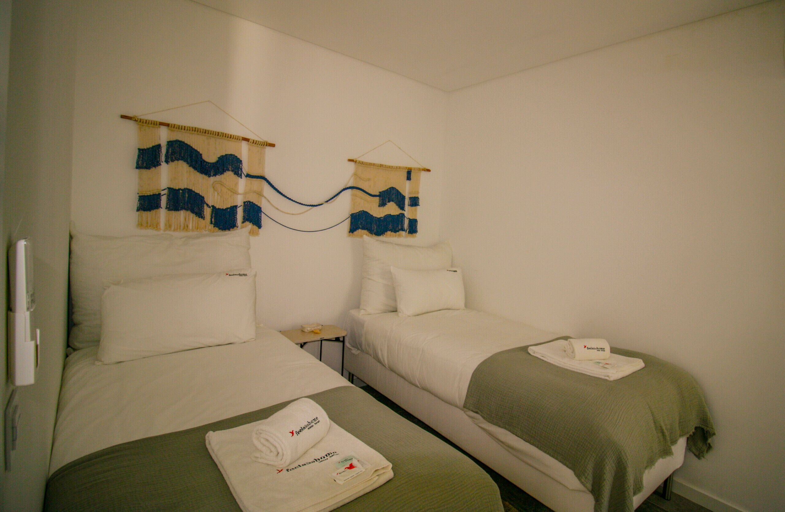 Ein Hotelzimmer mit zwei Betten, einem kleinen Tisch und einer Wandhalterung.