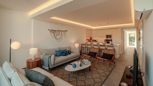 A modern living room with a sofa, coffee table, and a dining area with chairs. - FLH Vilamoura Boho Apartment with Terrace (Vilamoura)