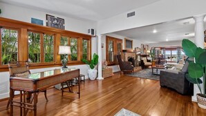 Ein geräumiges Wohnzimmer mit Holzböden, großen Fenstern und einem Kamin.