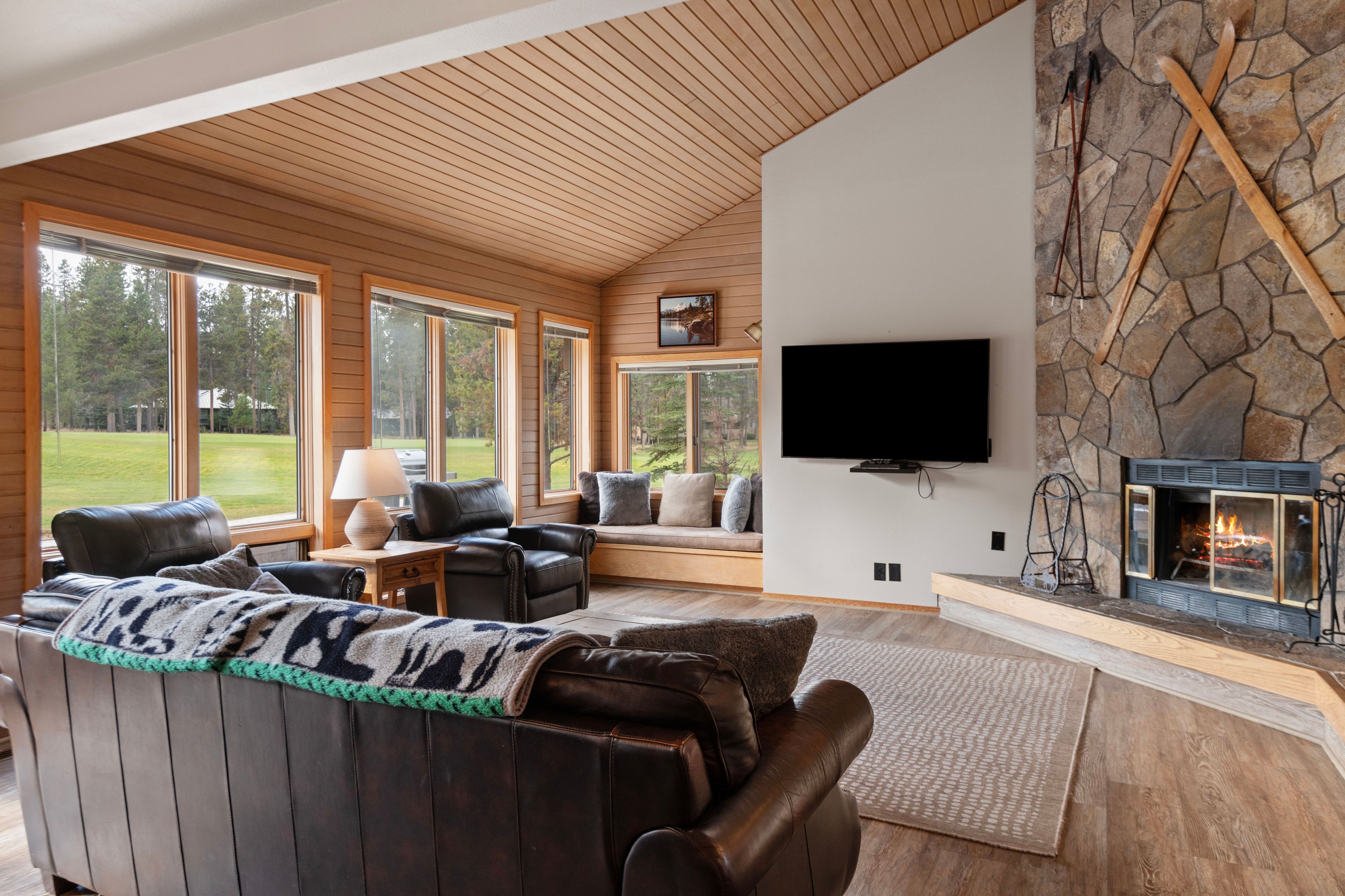 Living room with wood-paneled walls, leather seating, and a stone fireplace.