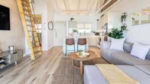 Ein modernes Interieur mit Essbereich, einer Couch, einer Holzlade und einer Küche im Hintergrund.