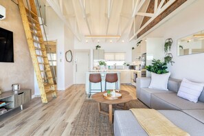 Ein modernes Interieur mit Essbereich, einer Couch, einer Holzlade und einer Küche im Hintergrund.