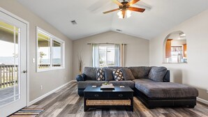 A living room with a sectional sofa, a coffee table, and a ceiling fan. - Beach House | Oceanfront + Fenced Yard (Crescent City)