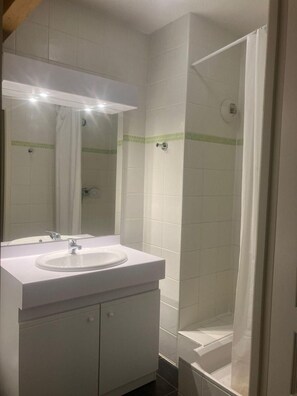 A bathroom with a white sink, mirror, and shower. - 3rd floor, fitness, swimming pool, sauna, balcony, parking, tv, ski locker, 70m², Saint Gervais (Saint-Gervais-les-Bains)