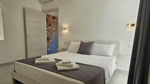 A hotel room with a large bed, a door with a colorful artwork, and a wall-mounted light fixture. - Diletta's Residence - Two-room apartment 2 (Sant'Isidoro)