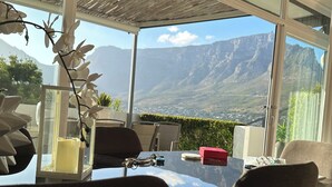 Un espace repas comprenant une table, des chaises et offrant une vue sur les montagnes.