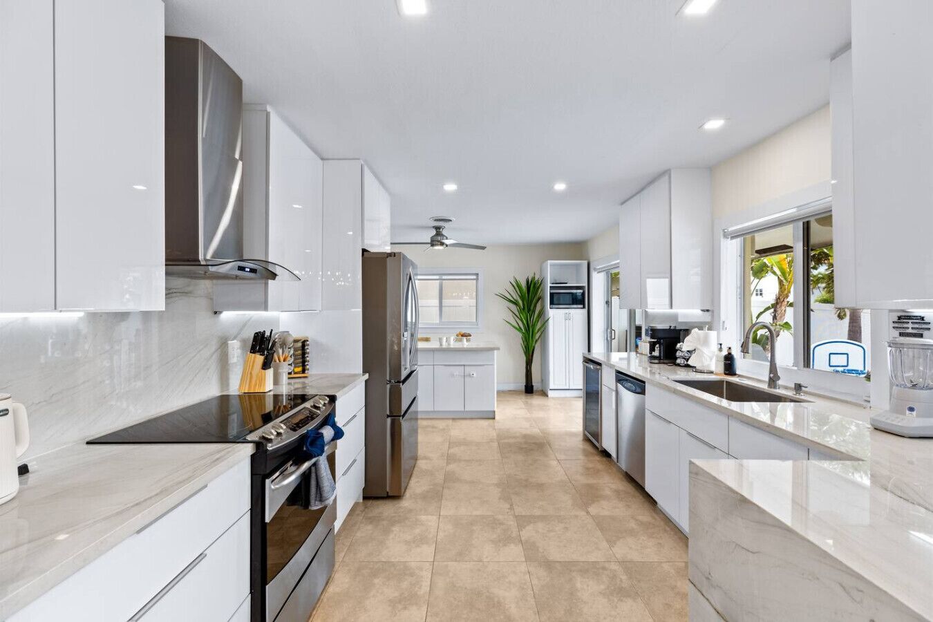 A modern kitchen with white cabinets, stainless steel appliances, and a marble countertop.