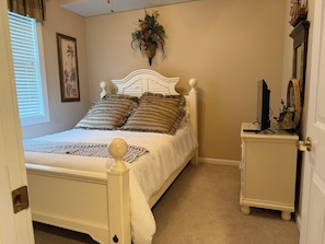 A bedroom with a bed, bedside table, and a wall-mounted plant.