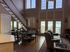 A spacious living area with a staircase, dining table, and seating.