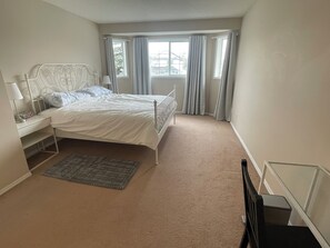 A bedroom with a bed, nightstand, lamp, and a window with curtains. - 10 min from airport and 20 to DT | 3 BR 4BA | 6 guests | 1G internet | Arcade (Calgary)