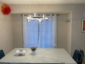 A dining area with a table, chairs, a chandelier, curtains, and a potted plant. - 10 min from airport and 20 to DT | 3 BR 4BA | 6 guests | 1G internet | Arcade (Calgary)