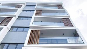 Um edifício com vários andares, varandas, janelas amplas e design arquitetônico moderno.
