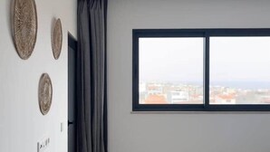 Un dormitorio con un ventanal grande, una cama y tres adornos en la pared.