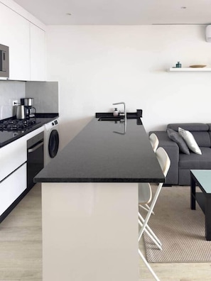 Une cuisine moderne dotée d’un îlot central, d’une cuisinière et d’un lave-linge.