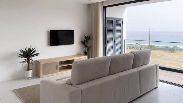 Een moderne woonkamer met een bank, televisie en uitzicht op de oceaan.