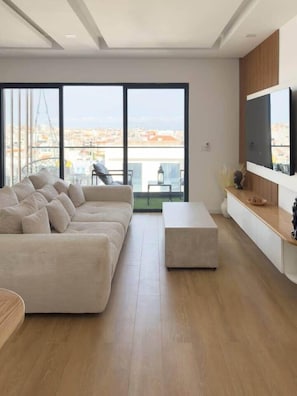 A modern living room with a sofa, a coffee table, and a TV mounted on the wall.