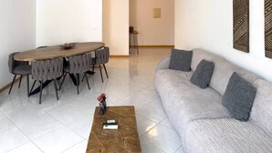 Ein modernes Wohnzimmer mit einer Couch, einem Couchtisch und einem Essbereich mit Tisch und Stühlen.