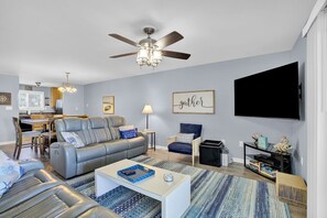 A modern living room with a sofa, armchairs, a coffee table, a TV, and a ceiling fan. - C 22 Sundown Condominiums (Perdido Key)