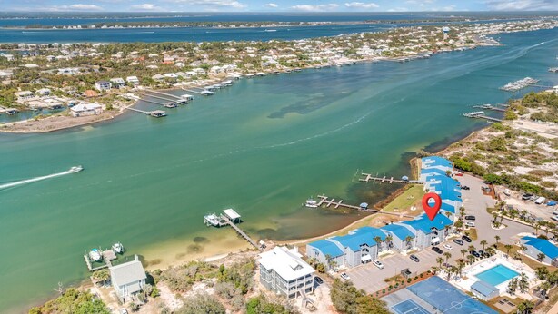 Luftaufnahme einer Küstenlandschaft mit einem Yachthafen, Booten und einem Hotel mit blauen Dächern.