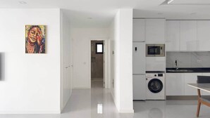 Cozinha moderna com eletrodomésticos embutidos, espaço de jantar e corredor que dá para outro cômodo.