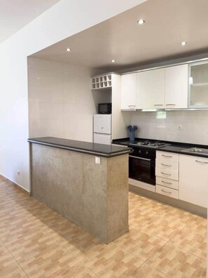 A modern kitchen with white cabinets, a black countertop, and a built-in oven.
