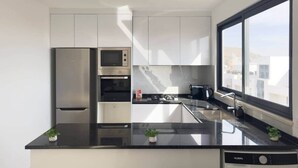 A modern kitchen with a dishwasher, a stove, and a sink. - Spacious 2 bdr aprt, rooftop pool - LCGR (Praia)