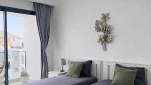 A modern bedroom with two beds, a nightstand, a lamp, and a decorative wall piece. - Spacious 2 bdr aprt, rooftop pool - LCGR (Praia)