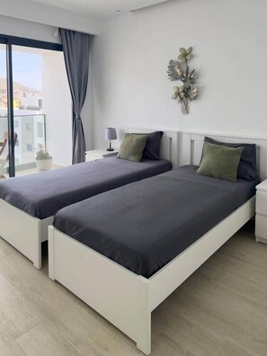 Une chambre moderne avec deux lits, une table de chevet, une lampe et un élément décoratif mural.
