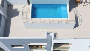 A rooftop pool with a clear blue water surface, surrounded by a white pool deck and a metal safety railing. - Spacious 2 bdr aprt, rooftop pool - LCGR (Praia)