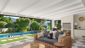 Ein modernes Wohnzimmer mit großem Fenster, Pool und Küchenbereich.