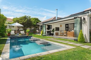 Une maison moderne dotée d’une piscine, de mobilier d’extérieur et d’un patio vitré.