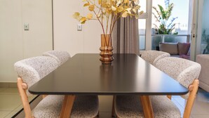 A dining table with chairs, a vase with flowers, and a view of the outdoors. - Beachfront Apartment | Table Mountain Views (Cape Town)