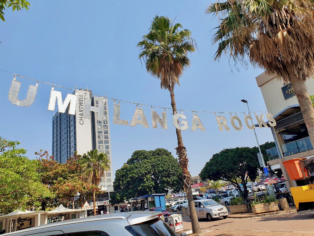 A street view with a sign reading 'UM HILANGA ROCKS' and a tall building labeled 'CHARTHILL WELL' in the background.