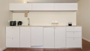 Een moderne keuken met witte kasten, een aanrecht, een koffiezetapparaat en een waterkoker.