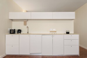 Eine moderne Küche mit weißen Schränken, einer Arbeitsplatte, einer Kaffeemaschine und einem Wasserkocher.